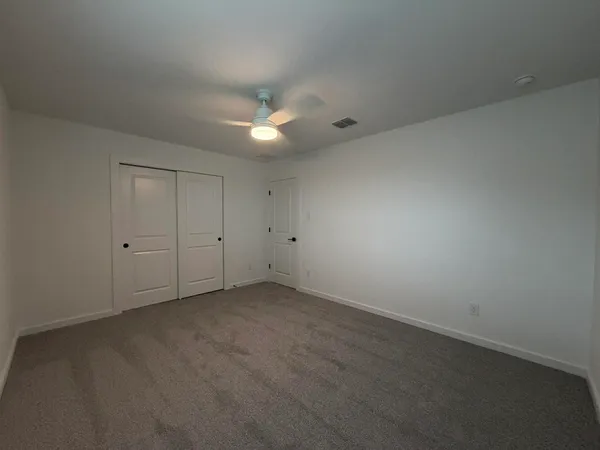 an empty room with a ceiling fan and a window
