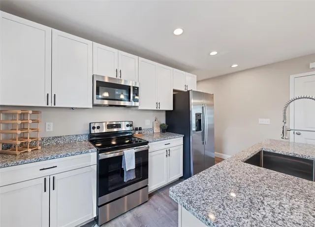 a kitchen with stainless steel appliances granite countertop a stove a sink and a refrigerator