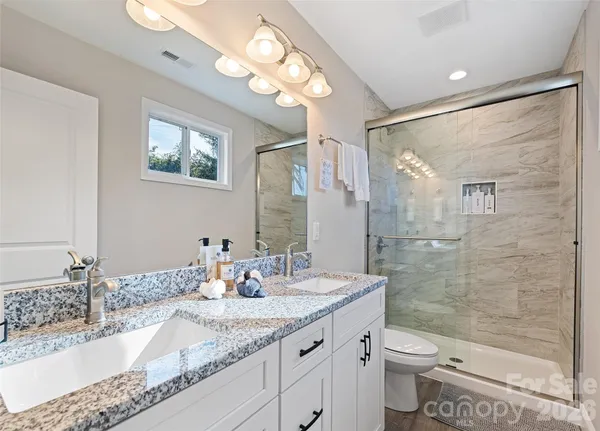 a bathroom with a granite countertop sink a toilet and shower