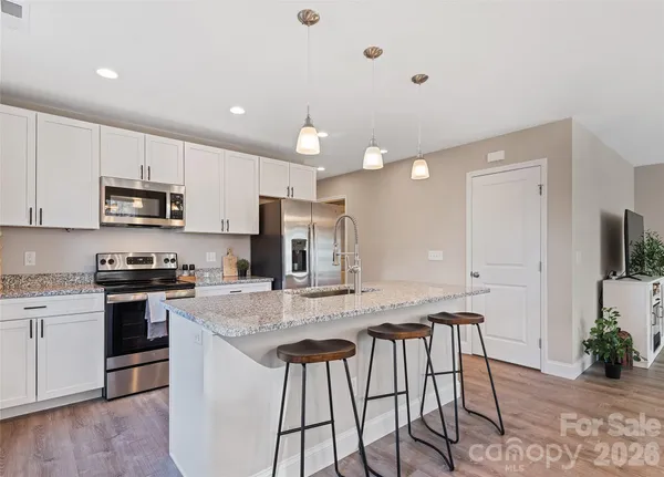 a kitchen with stainless steel appliances granite countertop a stove a sink a microwave a center island and furniture