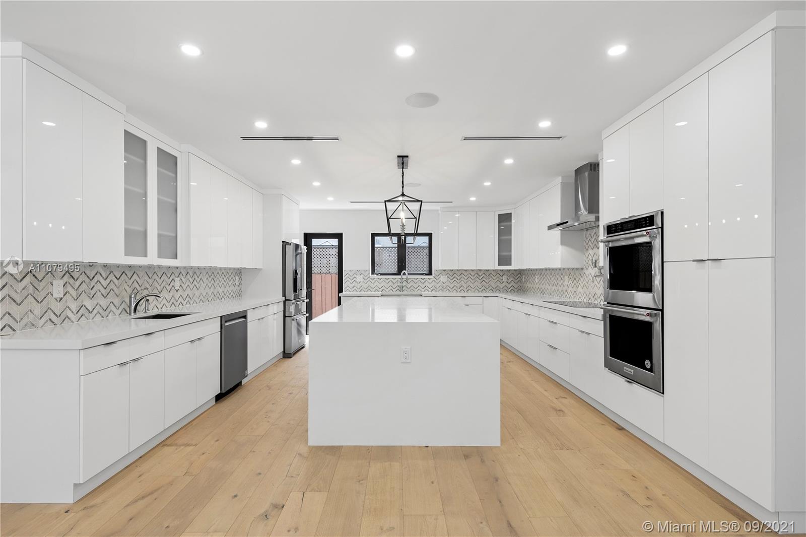 4450 Alton Road Miami Beach, FL 33140 - Photo 13 of 35 a large kitchen with stainless steel appliances kitchen island a large counter top and a stove top oven