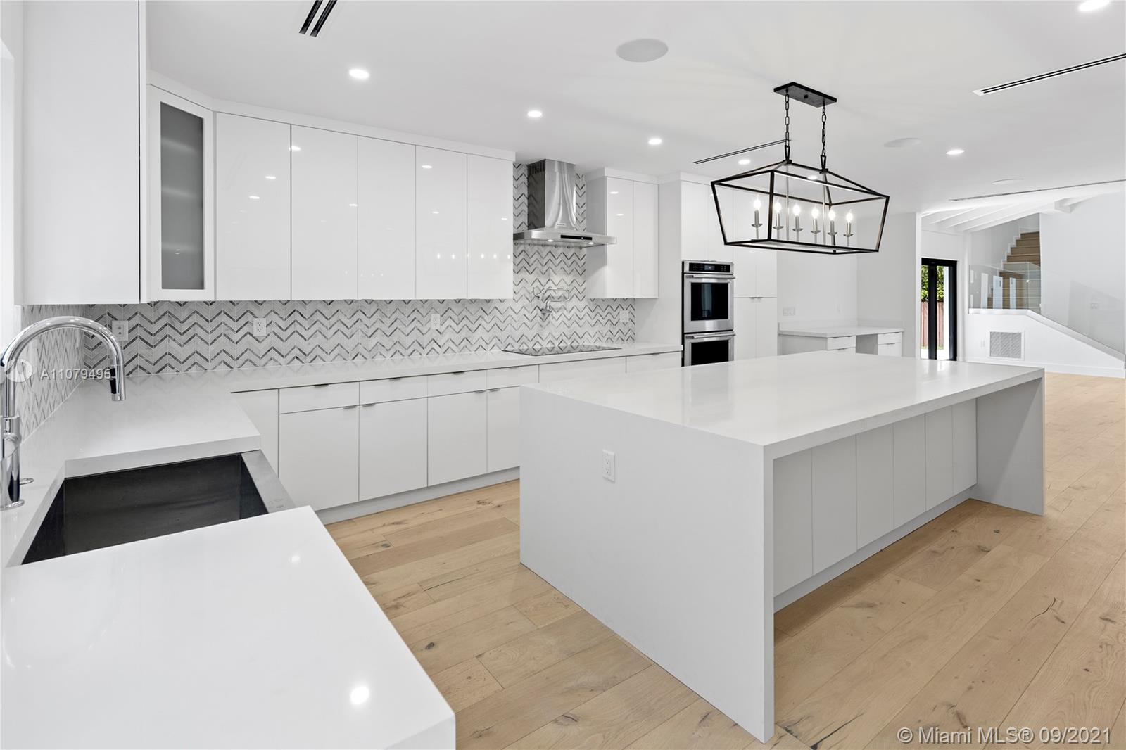 4450 Alton Road Miami Beach, FL 33140 - Photo 14 of 35 a kitchen with a sink a counter top space stainless steel appliances and cabinets