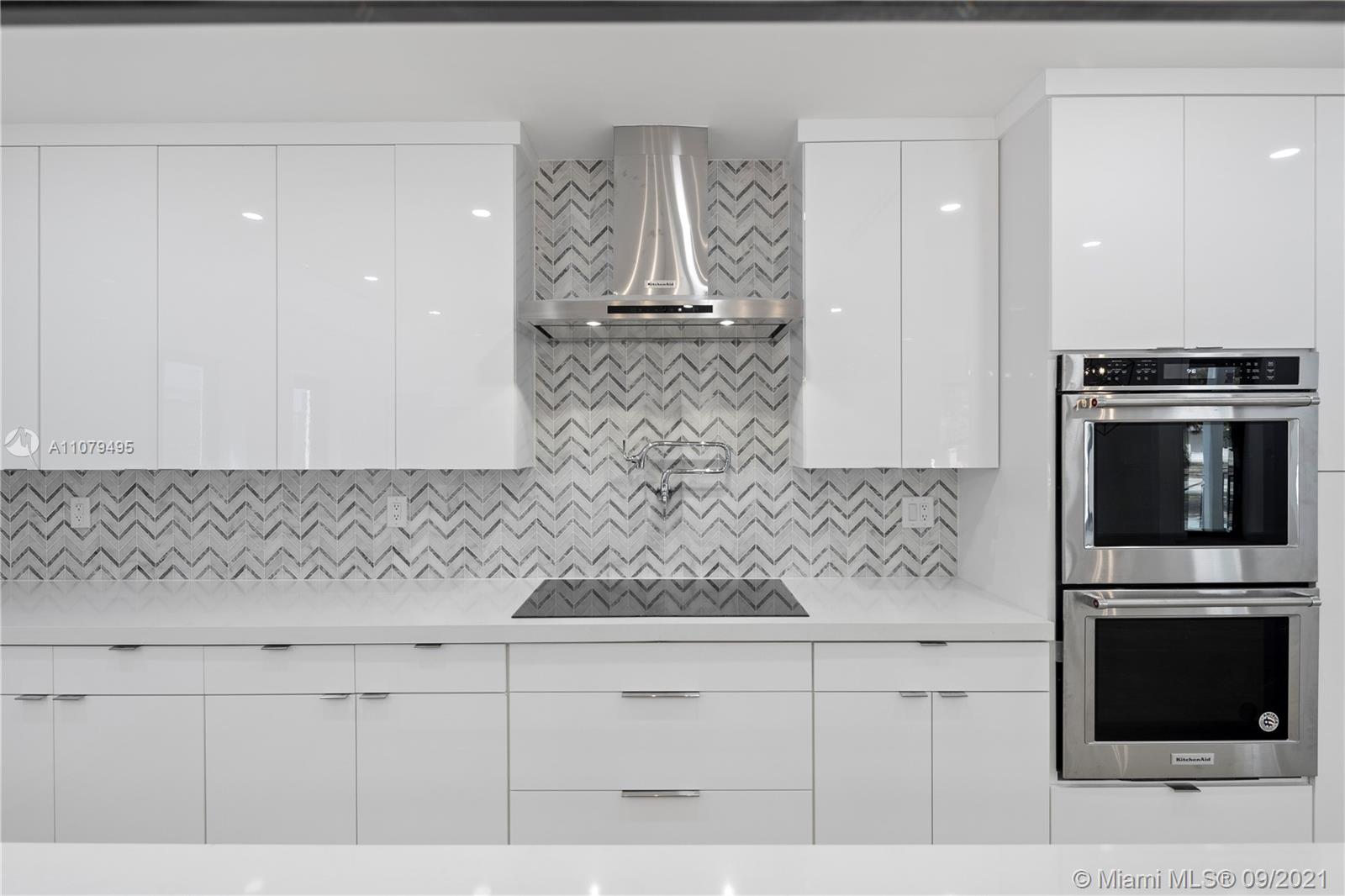 4450 Alton Road Miami Beach, FL 33140 - Photo 15 of 35 a kitchen with granite countertop white cabinets and stainless steel appliances