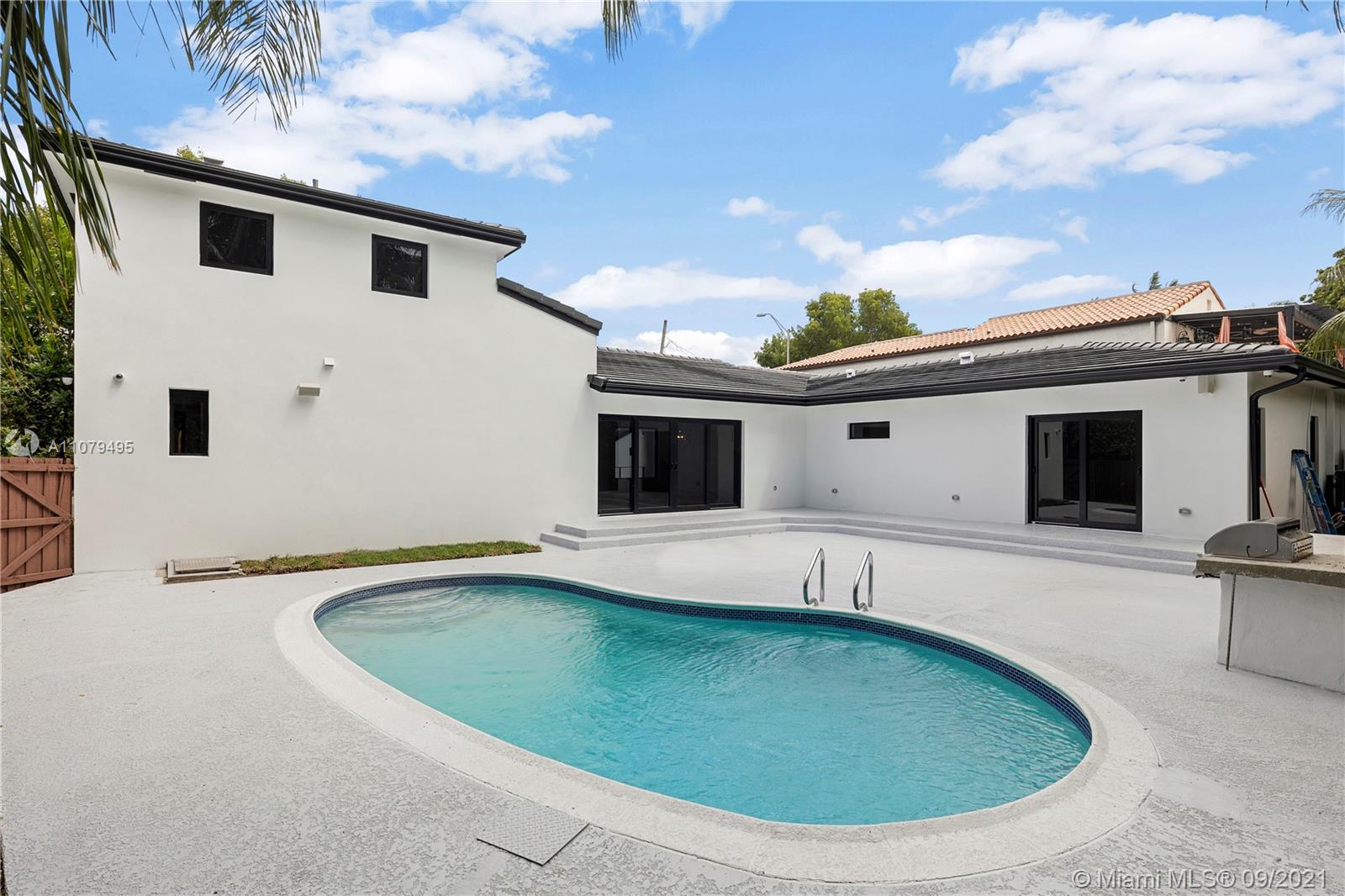 4450 Alton Road Miami Beach, FL 33140 - Photo 33 of 35 a view of a white house with a swimming pool and sitting area