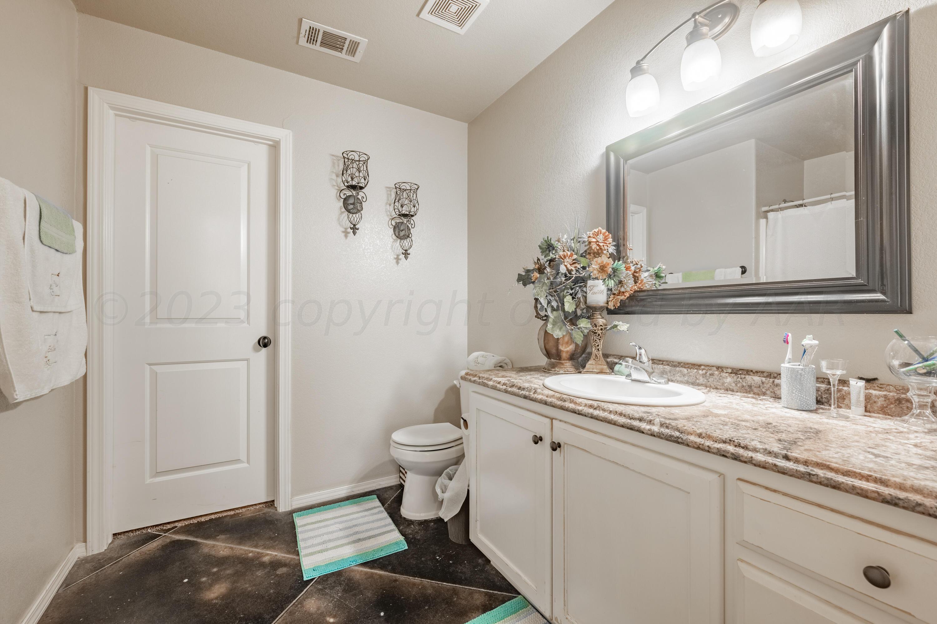 4502 Pine Street Amarillo, TX 79118 - Photo 12 of 20 a bathroom with a granite countertop sink a toilet and a mirror