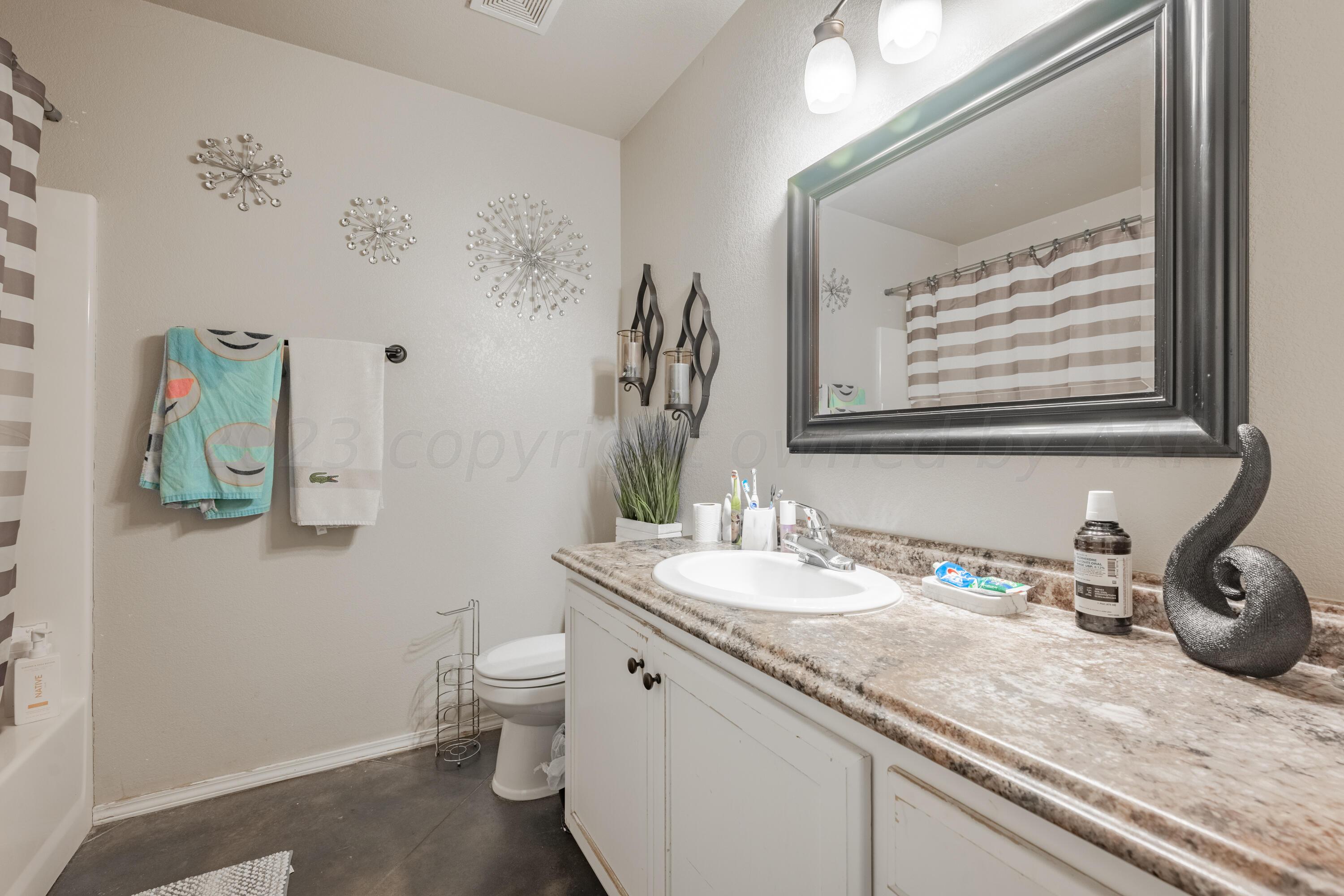 4502 Pine Street Amarillo, TX 79118 - Photo 17 of 20 a bathroom with a granite countertop sink a toilet and a mirror
