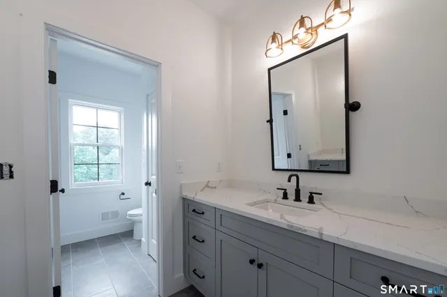 a bathroom with a sink a toilet and a mirror