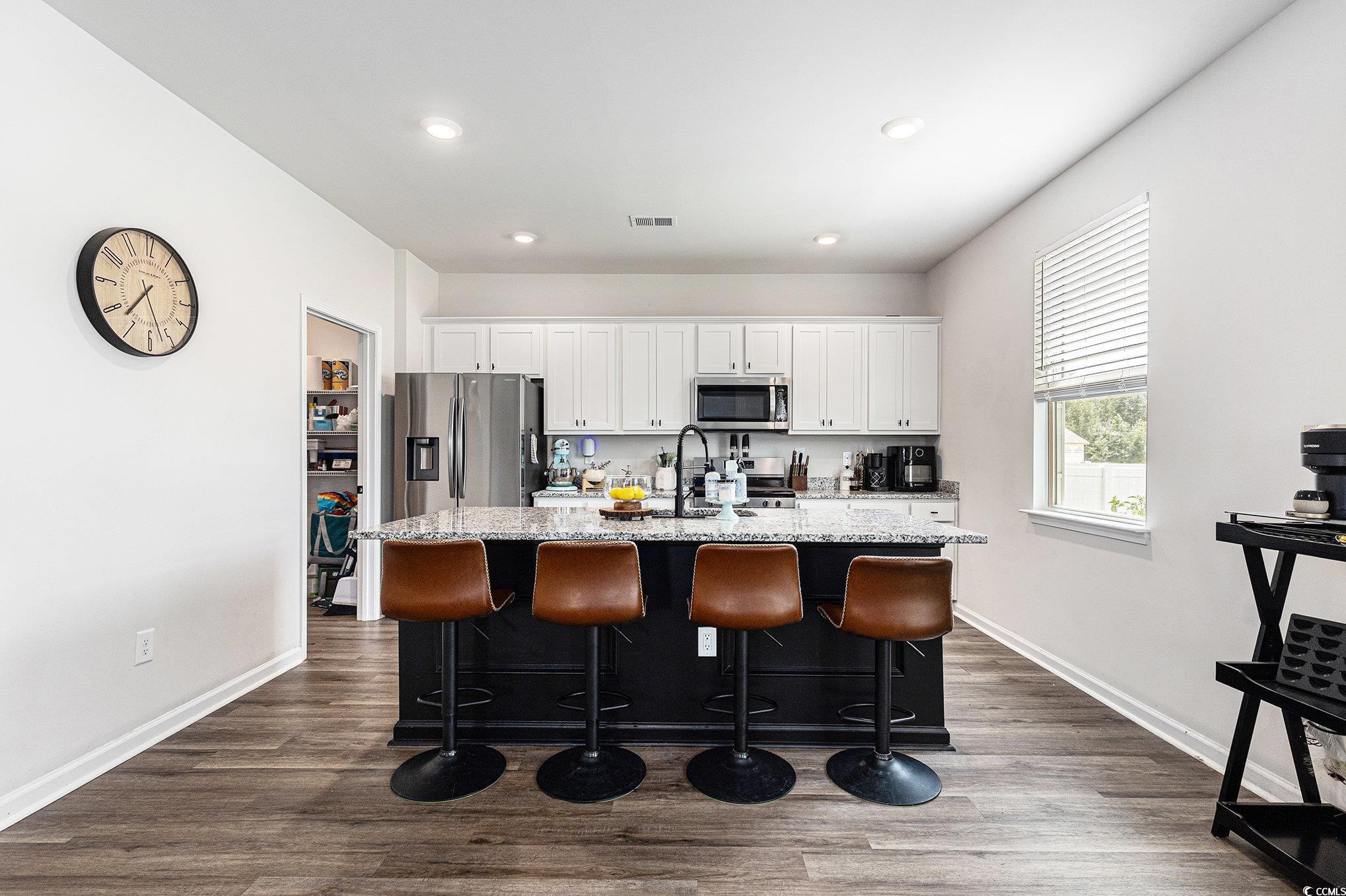 651 Choctaw Drive Conway, SC 29526 - Photo 7 of 37 Kitchen with a breakfast bar area, white cabinetry, dark wood-type flooring, a center island with sink, and light stone countertops