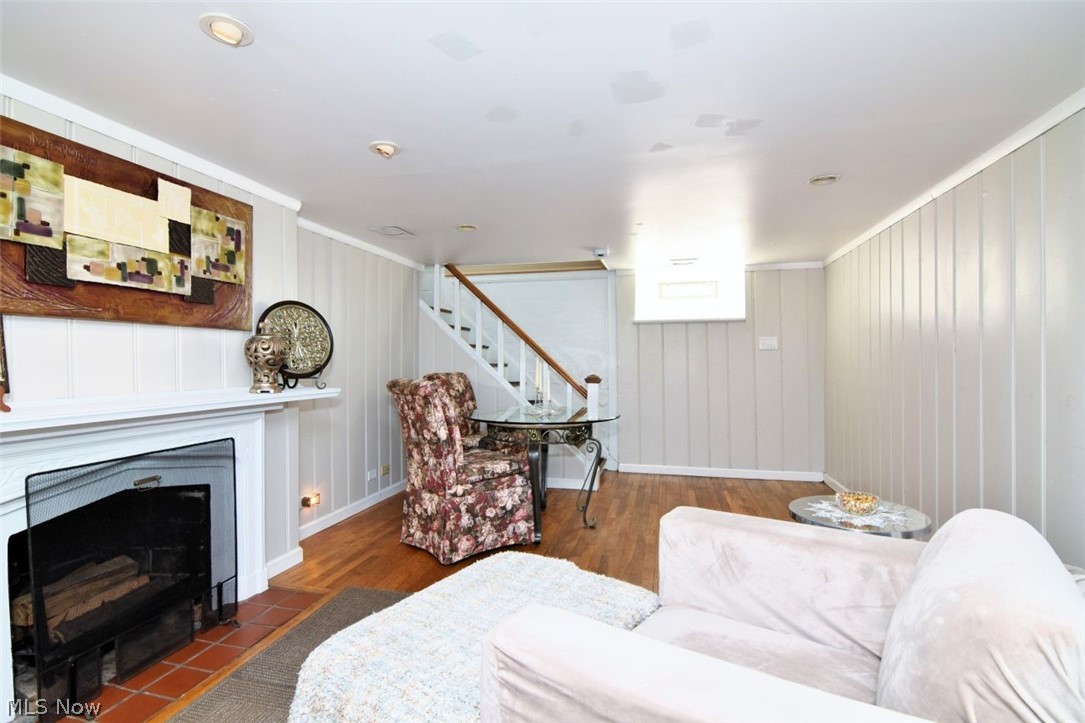 3451 Edison Road Cleveland Heights, OH 44121 - Photo 42 of 46 Hardwood flooring, painted paneled walls, white mantel fireplace with terracotta hearth, recessed lighting, and a staircase with wood handrails
