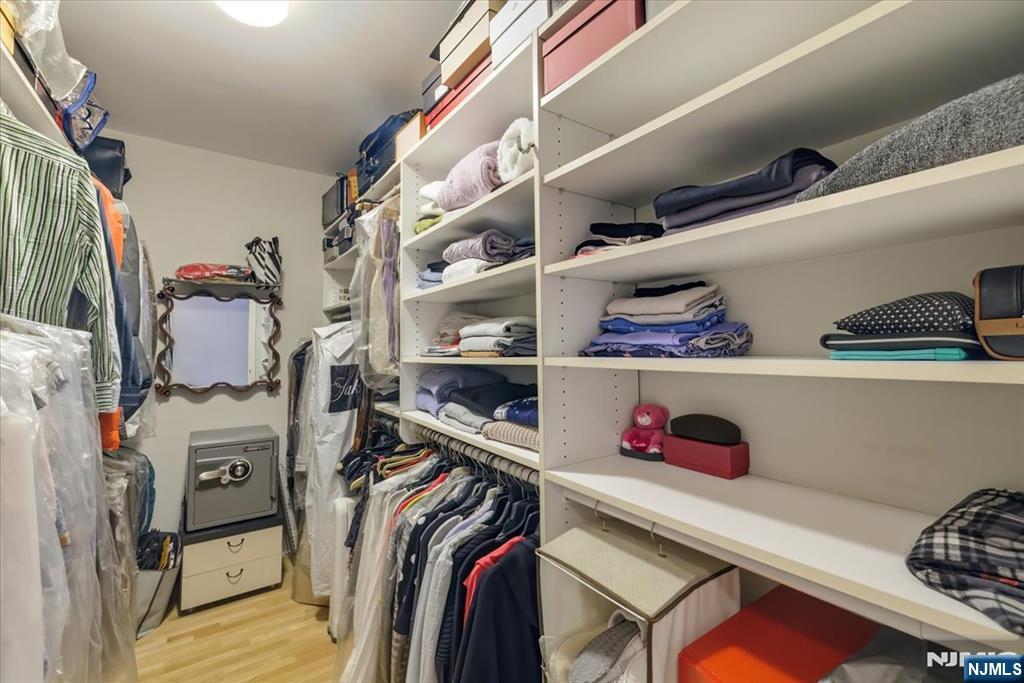 214 The Promenade, Unit 214 Edgewater, NJ 07020 - Photo 21 of 36 a view of walk in closet with clothes and shoes