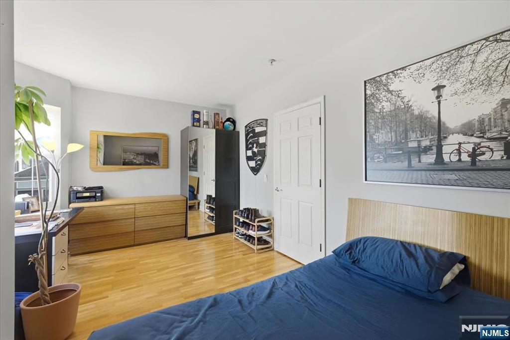 214 The Promenade, Unit 214 Edgewater, NJ 07020 - Photo 29 of 36 a bedroom with a bed and wooden floor