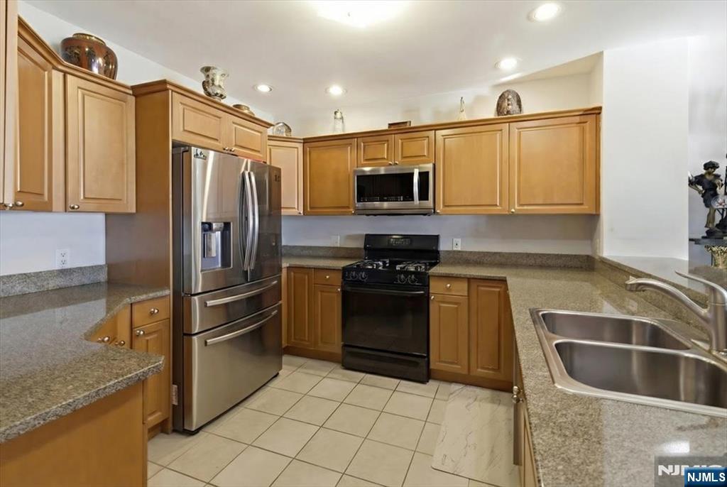 214 The Promenade, Unit 214 Edgewater, NJ 07020 - Photo 4 of 36 a kitchen with granite countertop a refrigerator and a sink