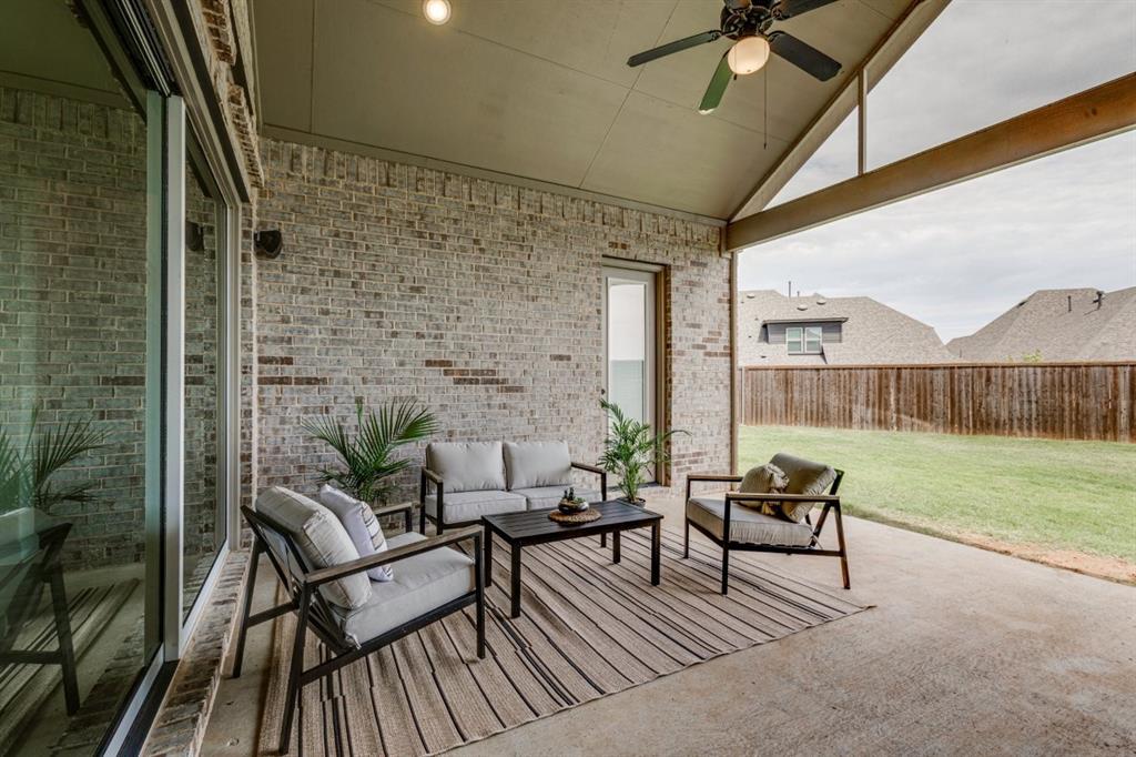 9613 Boulder Pt Road Oak Point, TX 75068 - Photo 17 of 28 Covered patio featuring a ceiling fan with integrated lighting, exposed wood beam, a brick exterior wall, and a sliding glass door