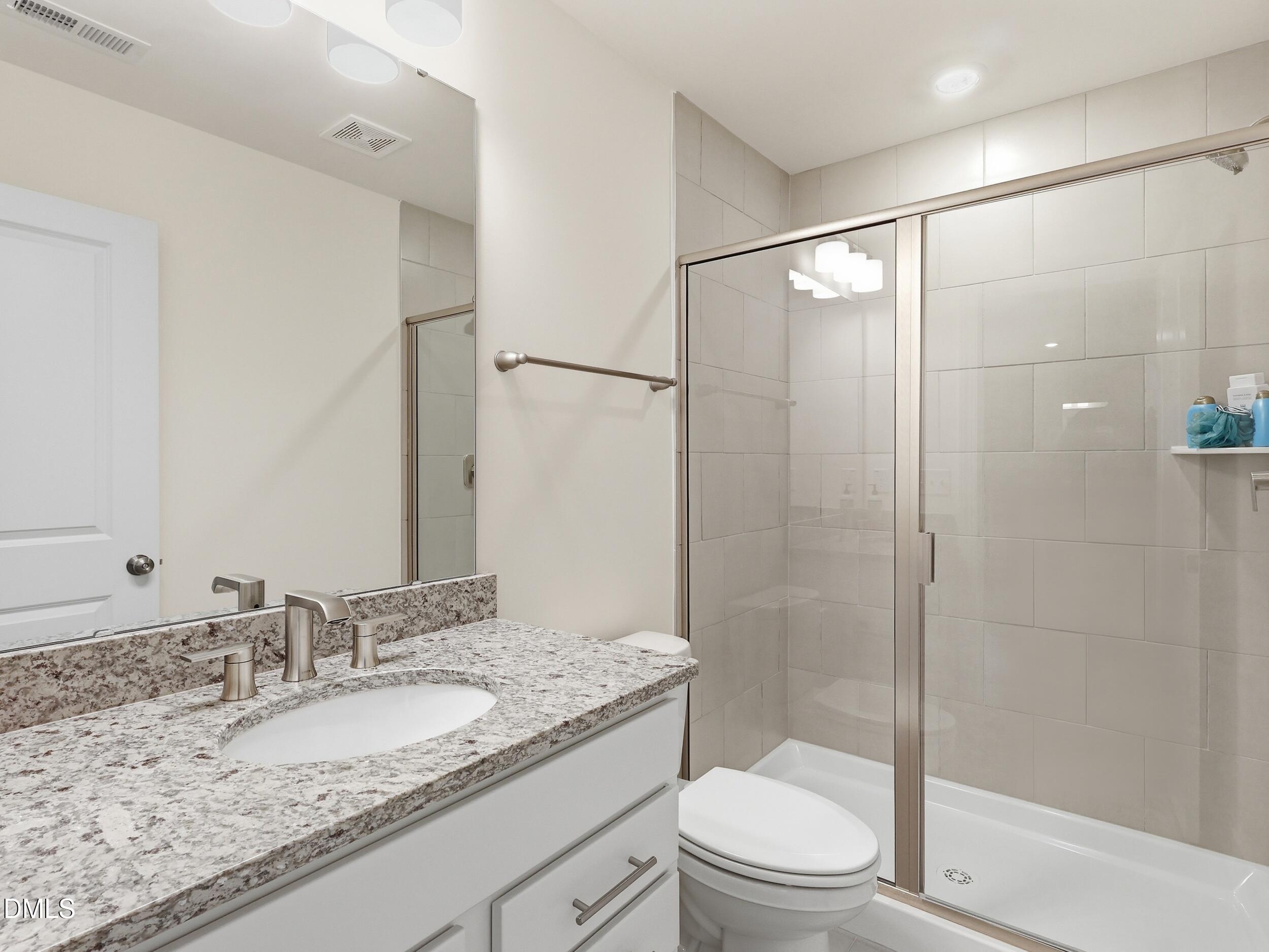 2709 Womble Ridge Drive New Hill, NC 27562 - Photo 39 of 60 a bathroom with a granite countertop sink toilet and shower