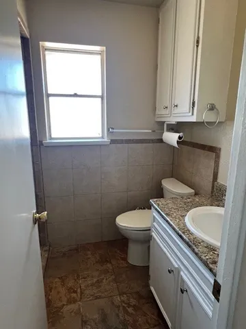 a bathroom with a granite countertop toilet sink and mirror