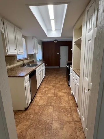 a kitchen with granite countertop a stove top oven a sink dishwasher and a refrigerator