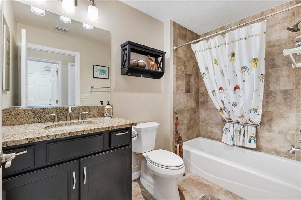 7351 Southeast 169th Cote Loop The Villages, FL 32162 - Photo 19 of 32 a bathroom with a granite countertop sink toilet and shower