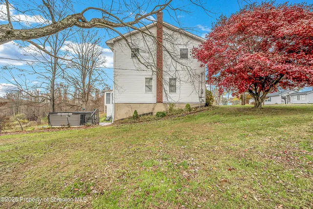 a view of a house with a yard and a large tree