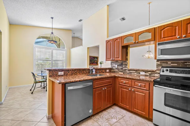 a kitchen with stainless steel appliances granite countertop a stove a sink and a microwave