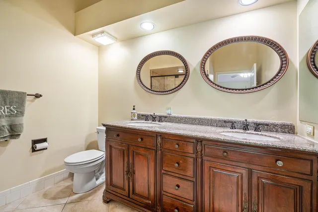 a bathroom with a granite countertop toilet a sink and a mirror