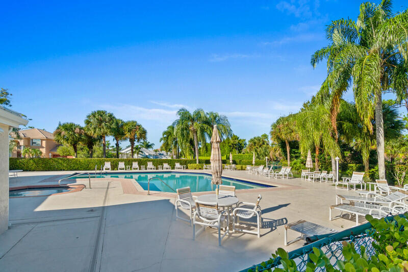 8918 Southeast Riverfront Terrace Jupiter, FL 33469 - Photo 39 of 43 a view of a swimming pool with lawn chairs under an umbrella