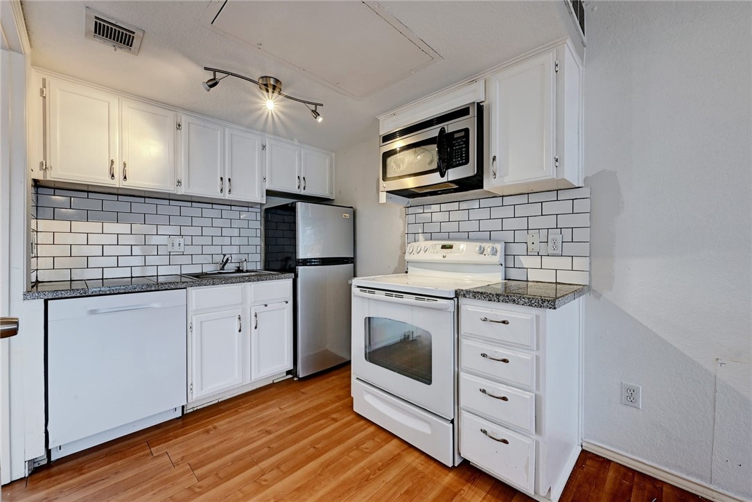 701 Nelray Boulevard, Unit 4 Austin, TX 78751 - Photo 1 of 1 a kitchen with white cabinets stainless steel appliances and wooden floor