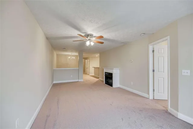 an empty room with chandelier fan and windows