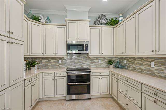 8777 Yucatan Court Naples, FL 34113 - Photo 4 of 41 a kitchen with white cabinets and stainless steel appliances