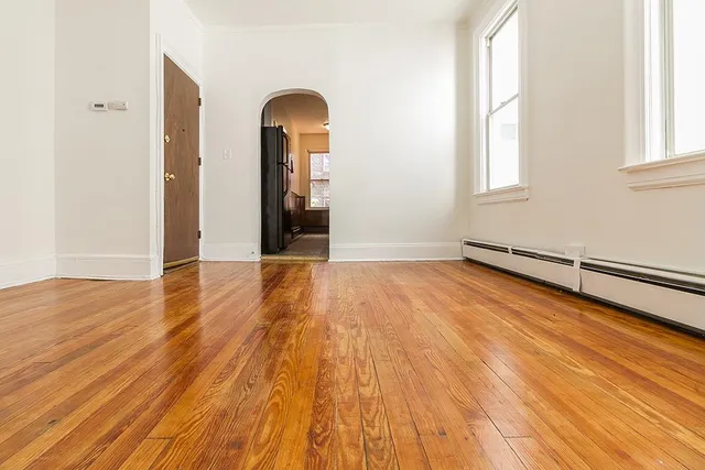 an empty room with wooden floor and windows