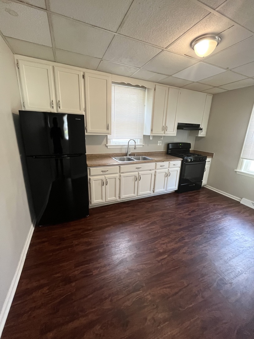 21142 Locust Street Matteson, IL 60443 - Photo 5 of 16 a kitchen with granite countertop a refrigerator a sink dishwasher a stove and white cabinets with wooden floor