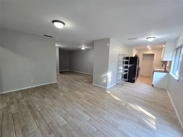 an empty room with wooden floor and large windows