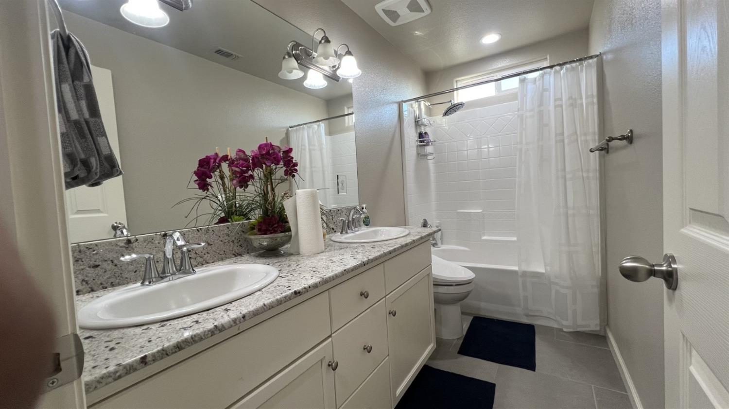 3525 Cordova Avenue Clovis, CA 93619 - Photo 25 of 35 a bathroom with a granite countertop sink a toilet a shower and a mirror