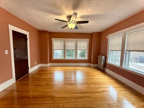 a view of an empty room with window and wooden floor