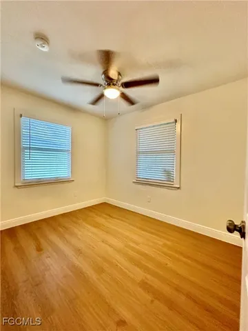 a view of an empty room with wooden floor and a ceiling fan