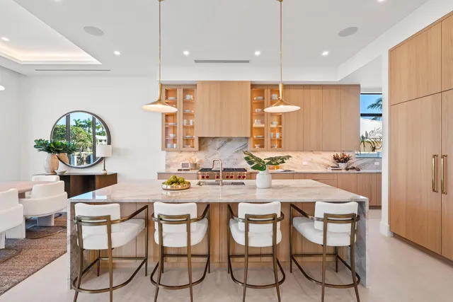 a kitchen with stainless steel appliances kitchen island granite countertop a dining table chairs sink and white cabinets