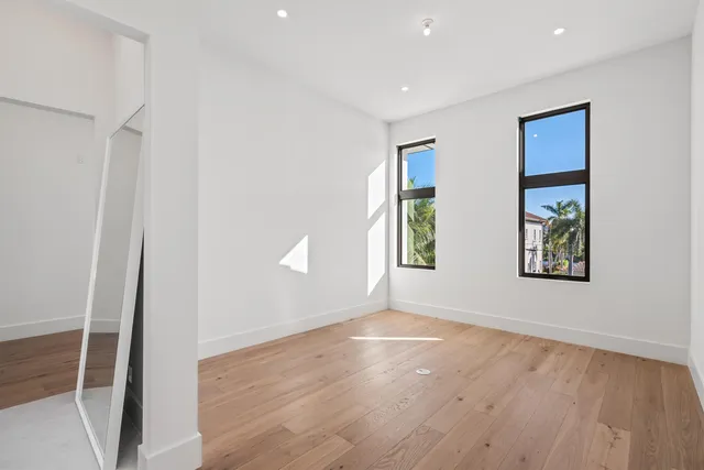 a view of an empty room with window and wooden floor