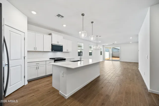 a large kitchen with kitchen island a stove a sink a center island and wooden floor
