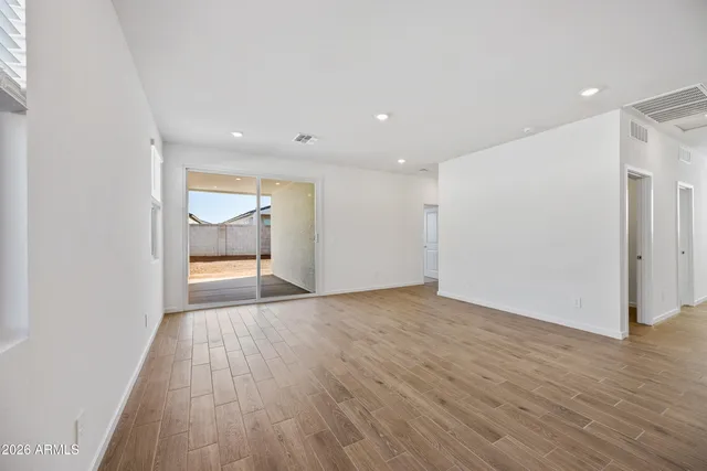 a view of an empty room with wooden floor and window