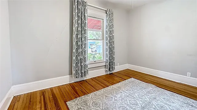 a view of a bedroom with wooden floor and a window