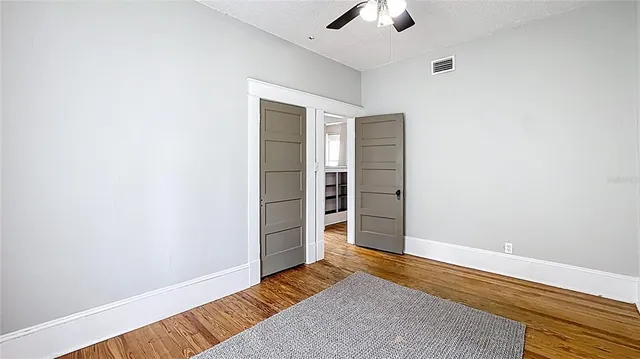 an empty room with a hardwood and ceiling fan