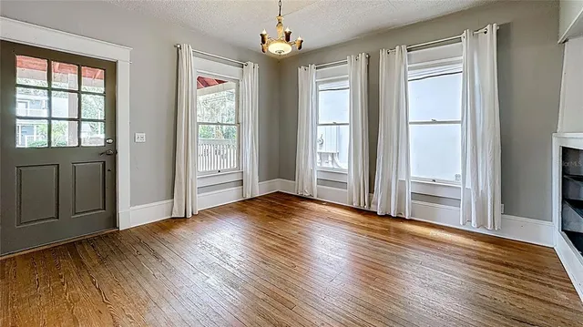 an empty room with wooden floor cabinet and windows