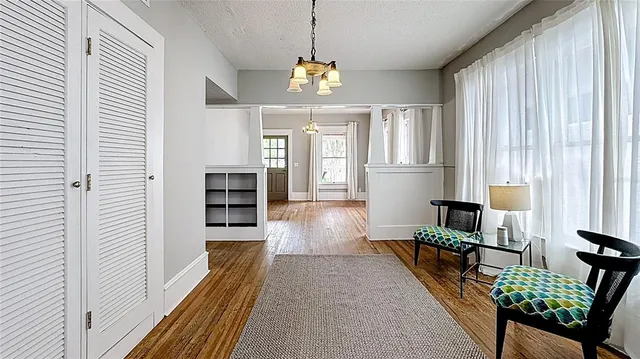 a hallway with a dining table chairs wooden floor and a chandelier