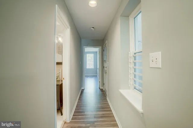 a view of a hallway with wooden floor and a bathroom
