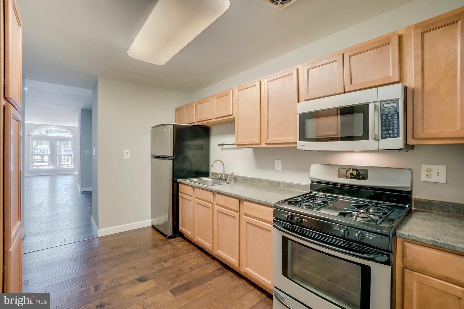 1522 East Baltimore Street, Unit 1 Baltimore, MD 21231 - Photo 4 of 26 a kitchen with stainless steel appliances granite countertop a stove microwave and refrigerator