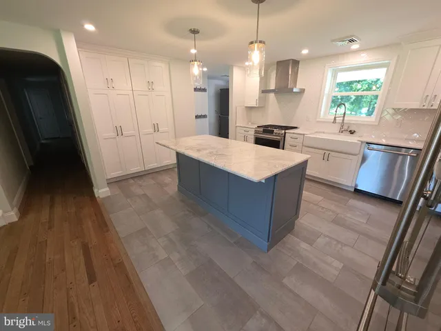 a large kitchen with stainless steel appliances a large counter top a stove a sink dishwasher and a refrigerator