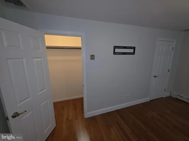 a view of an empty room with wooden floor and closet