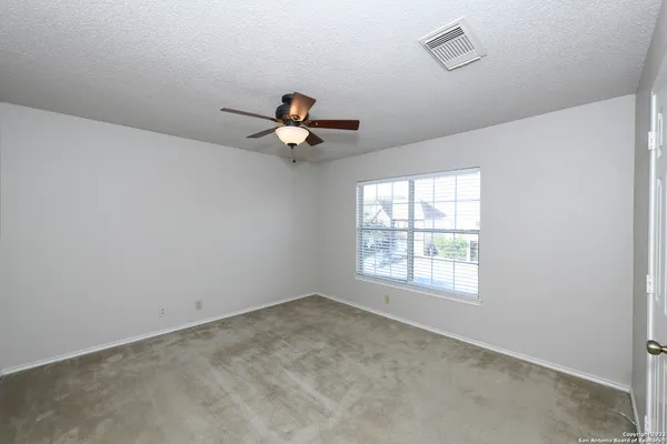an empty room with a window and a fan