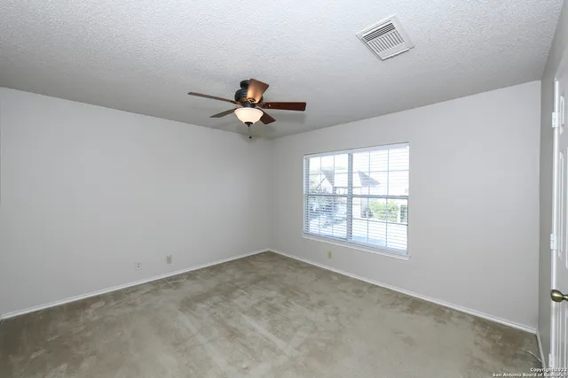 an empty room with a window and a fan