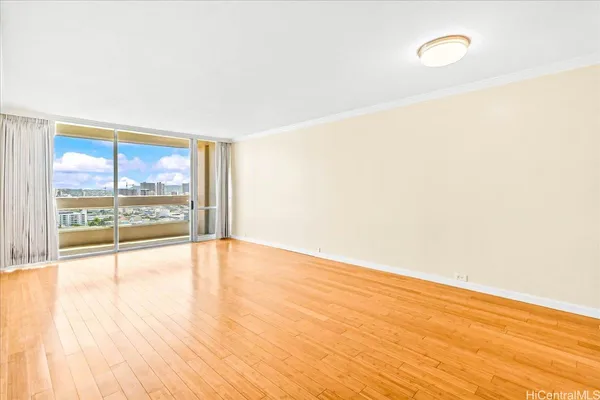 a view of an empty room with wooden floor and a window
