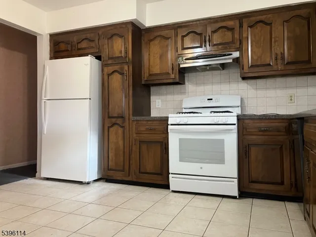 a kitchen with stainless steel appliances granite countertop a refrigerator a stove and a sink